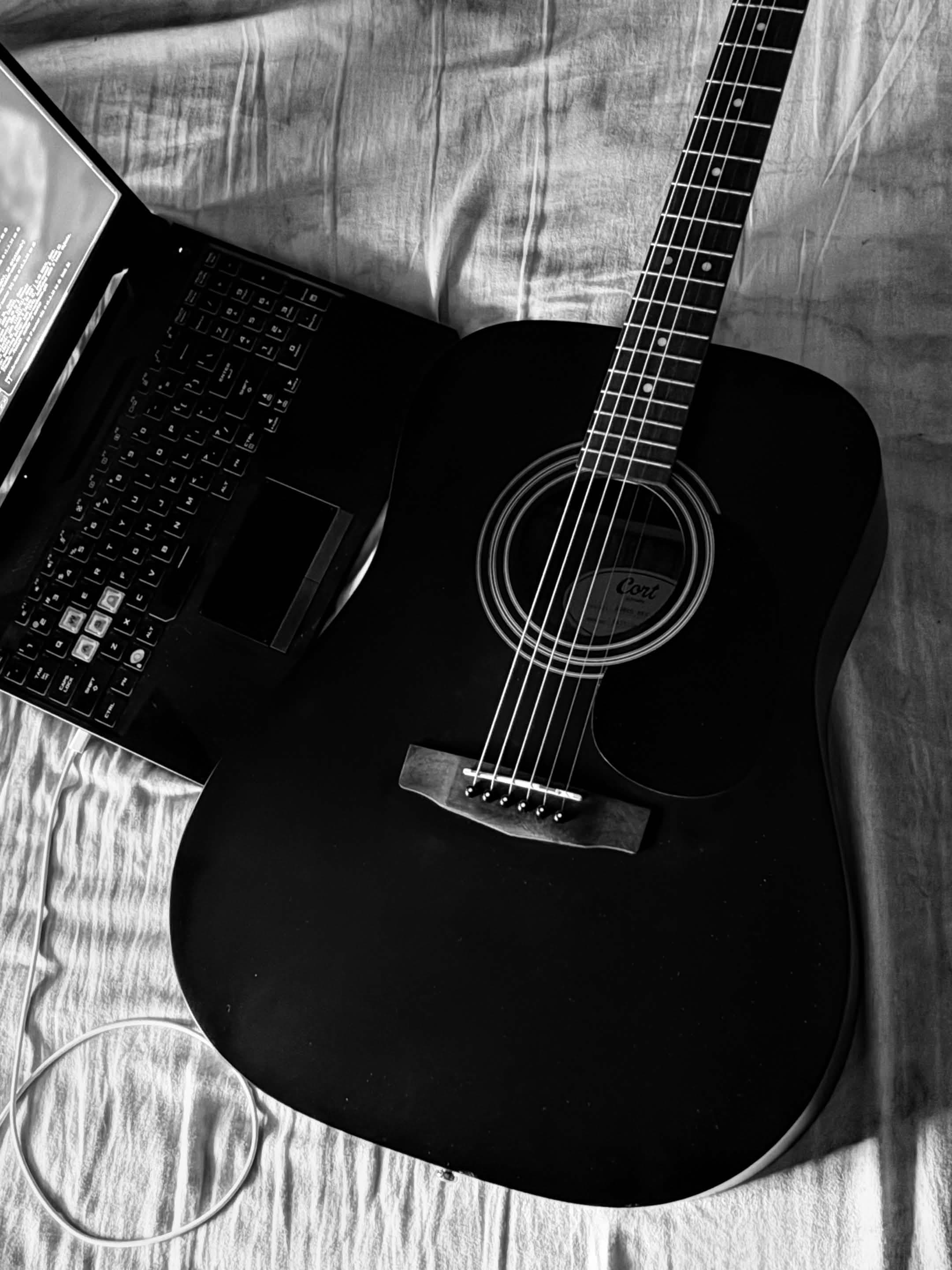 A dreadnought acoustic guitar on the bed